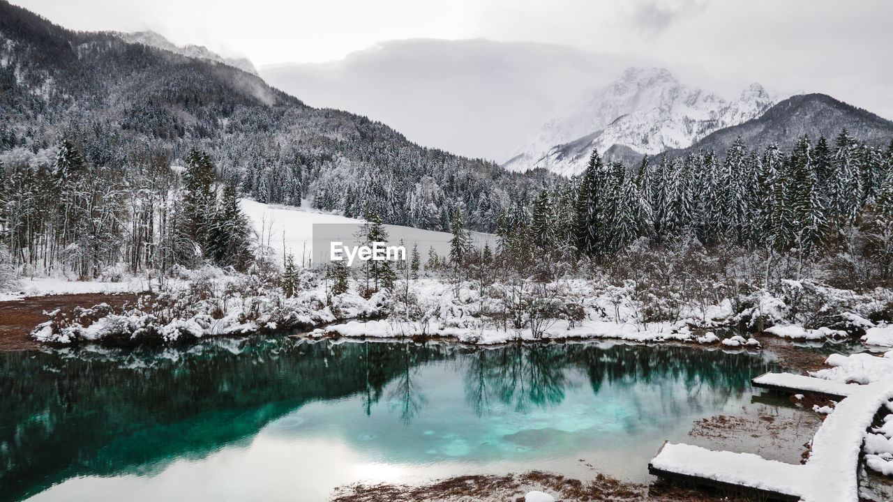 Scenic view of lake by snowcapped mountains against sky