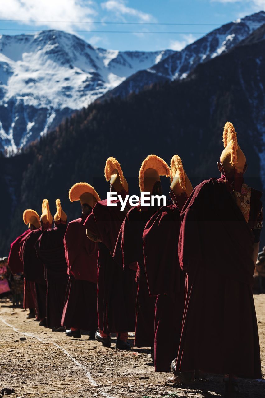 Rear view of monks standing by snowcapped mountain