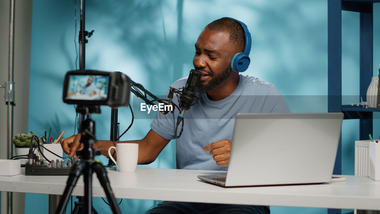 Smiling young man filming through camera