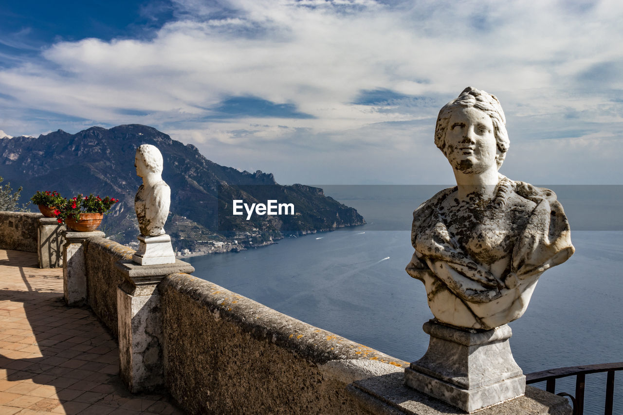 STATUE AGAINST SKY WITH MOUNTAIN IN BACKGROUND AGAINST CLOUDY BLUE AND CLOUDS