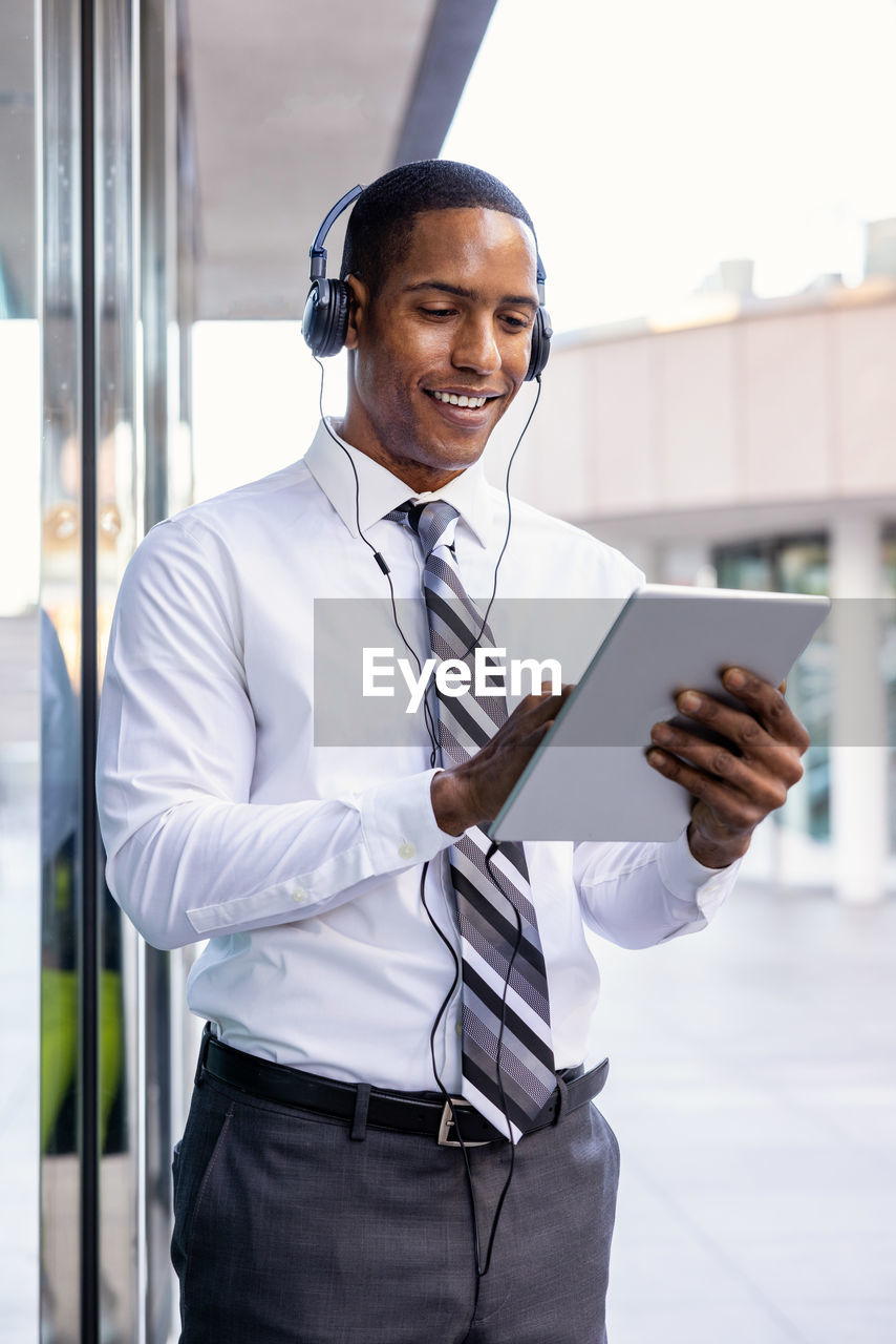 young man using mobile phone while standing in office