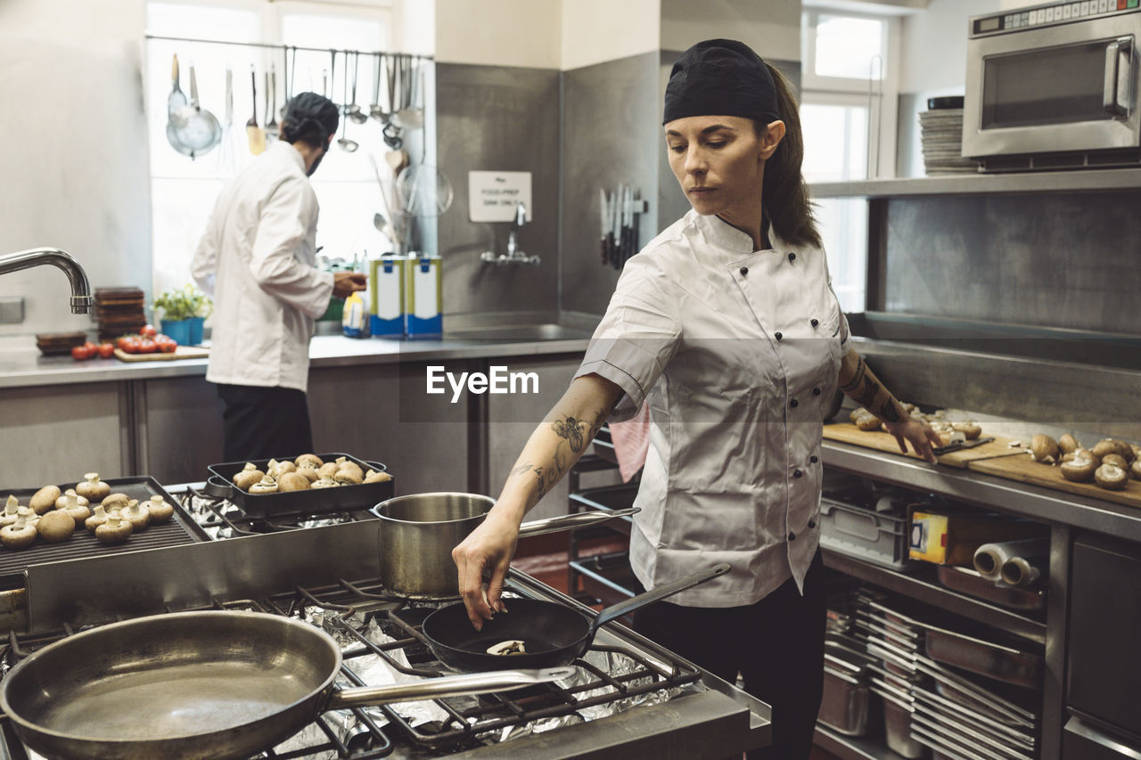 Male and female chefs preparing food in commercial kitchen