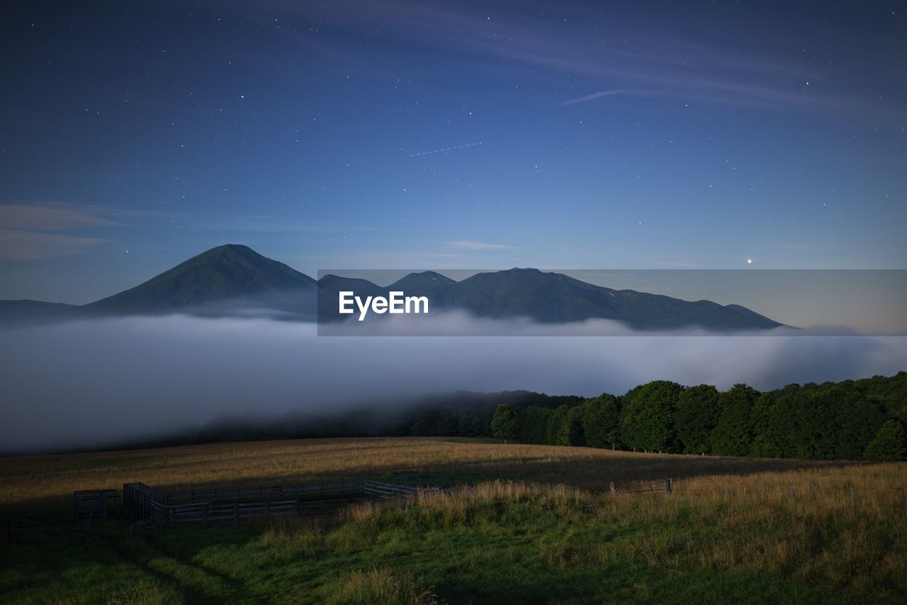 Scenic view of landscape in foggy weather against sky at dawn