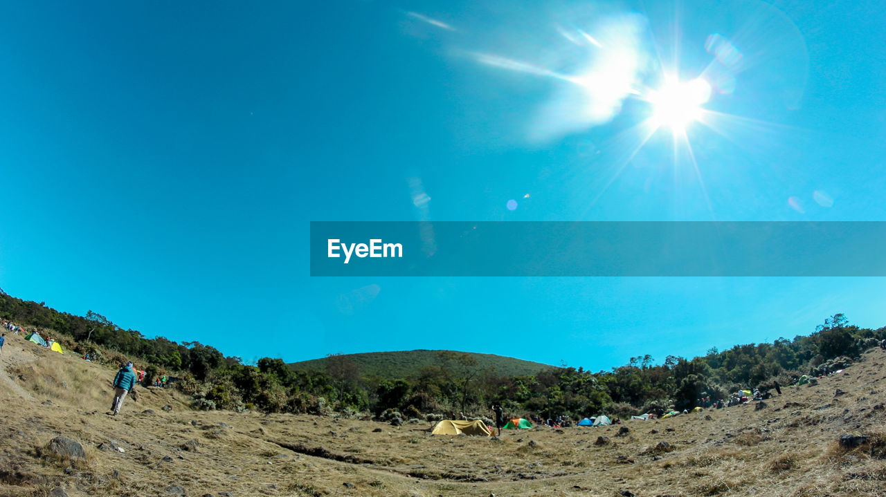 Panoramic view of people outside tent on field during sunny day