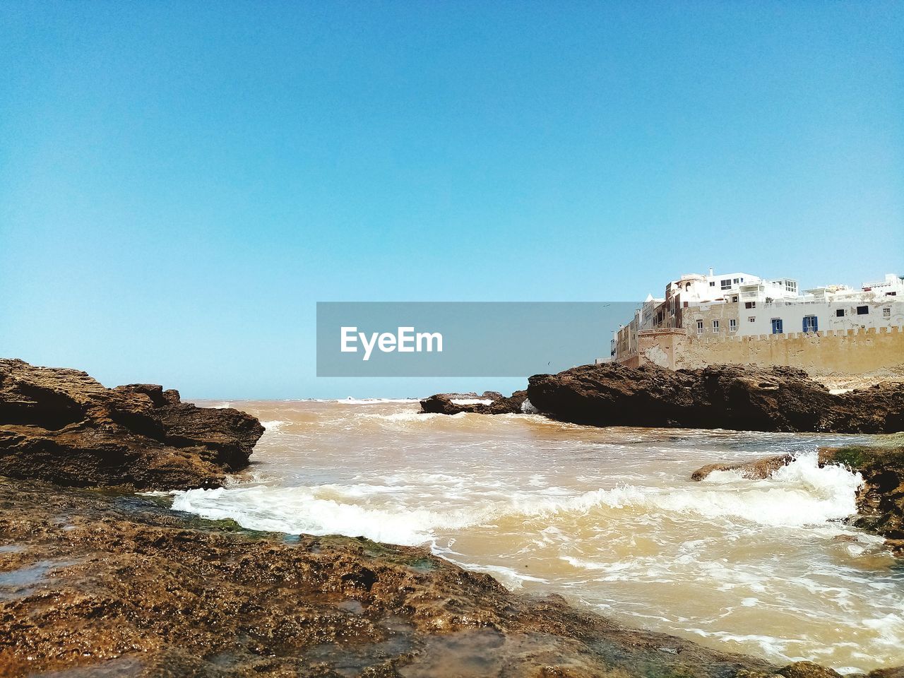 Rocks on beach against clear blue sky