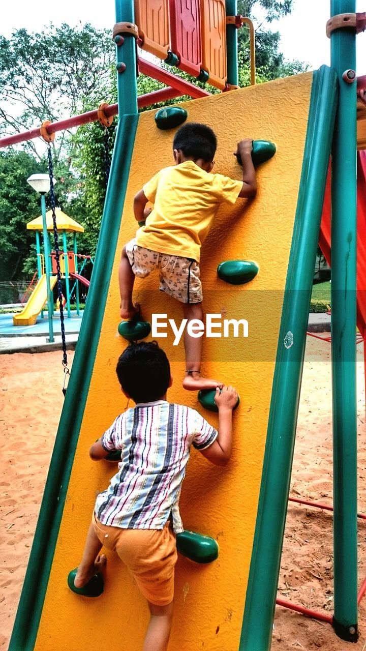 Rear view of boys climbing on metal at playground