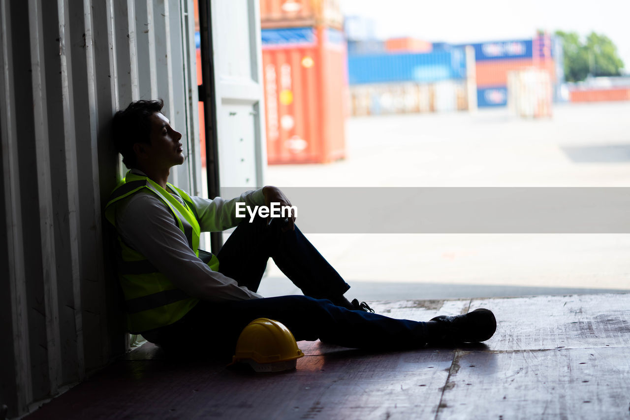 SIDE VIEW OF SENIOR MAN SITTING ON FLOOR