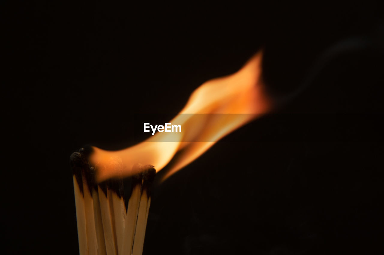 CLOSE-UP OF BURNING CANDLES AGAINST BLACK BACKGROUND