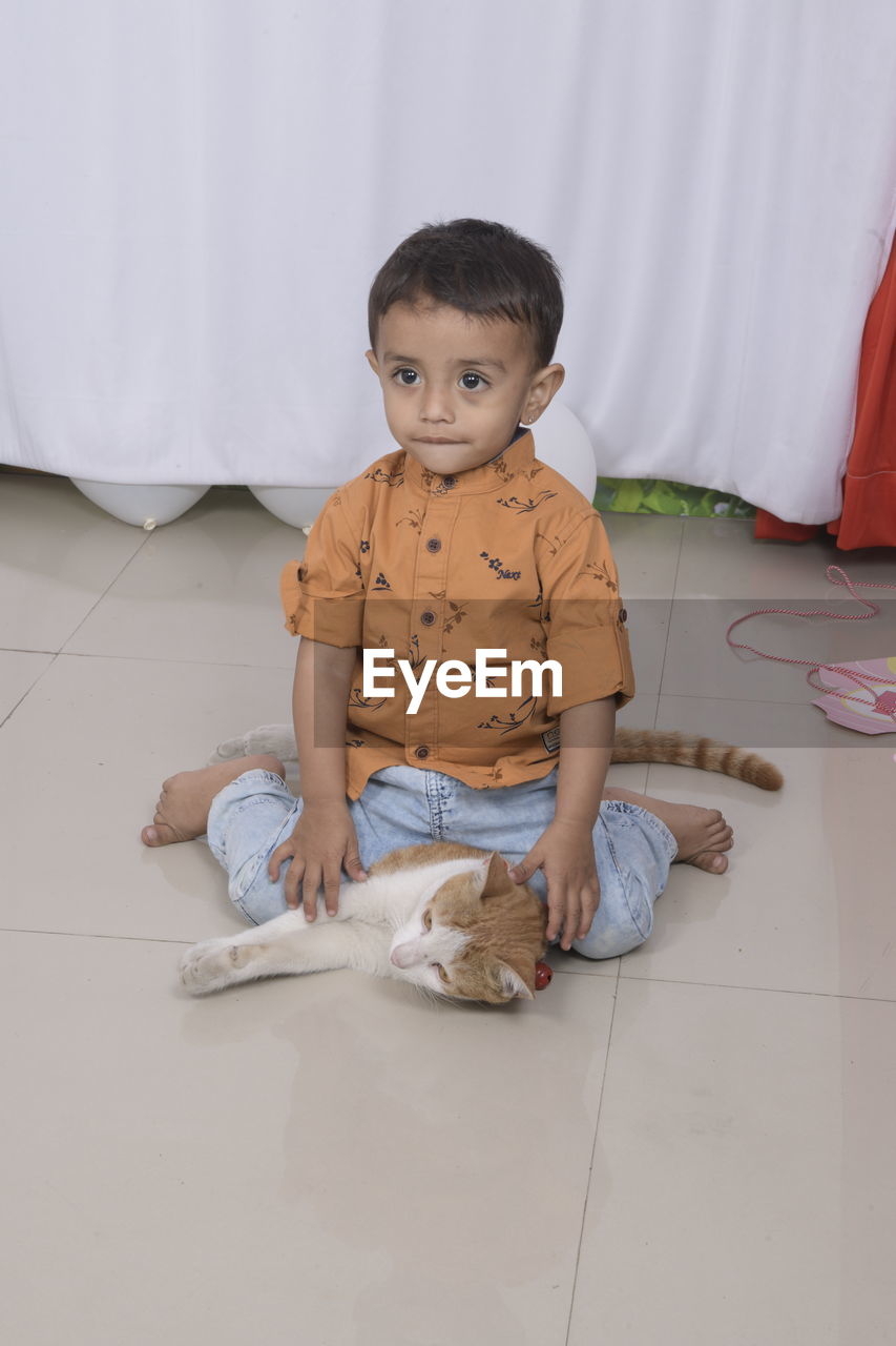 Boy sitting on cat at home