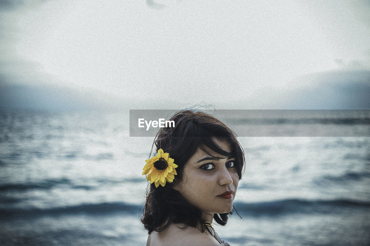 Portrait of young woman against sea