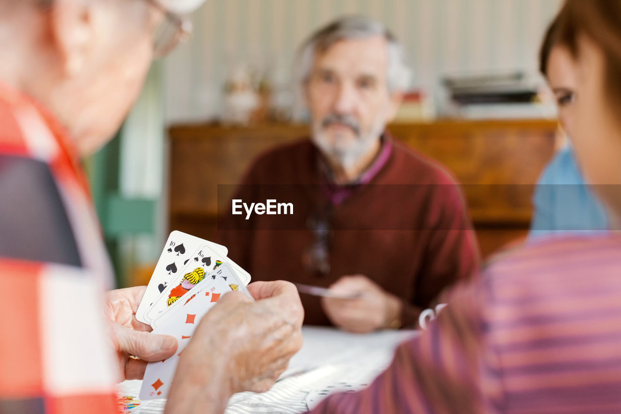 Cropped image of senior woman playing cards with family at home