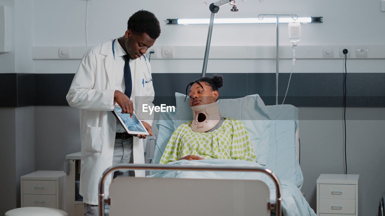Doctor showing digital tablet to patient at hospital