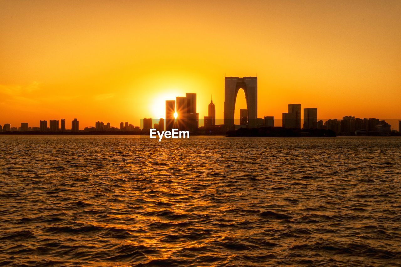 Modern cityscape against sky during sunset