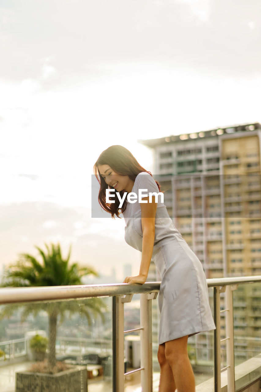 PORTRAIT OF WOMAN STANDING AGAINST RAILING