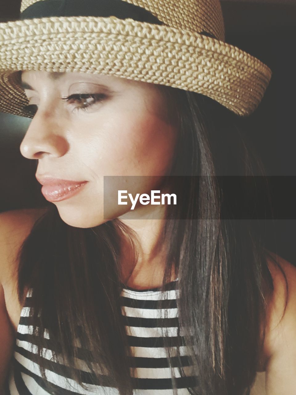 Close-up of thoughtful young woman wearing wicker hat