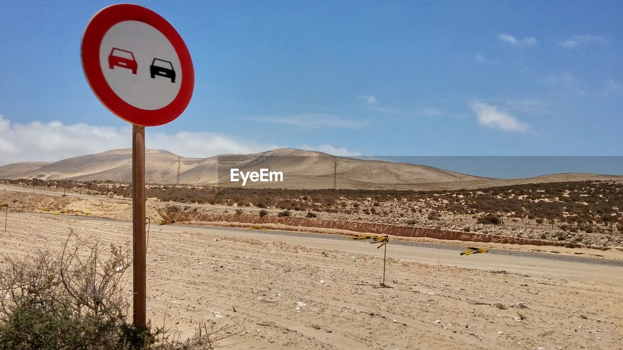 ROAD SIGN AGAINST MOUNTAIN