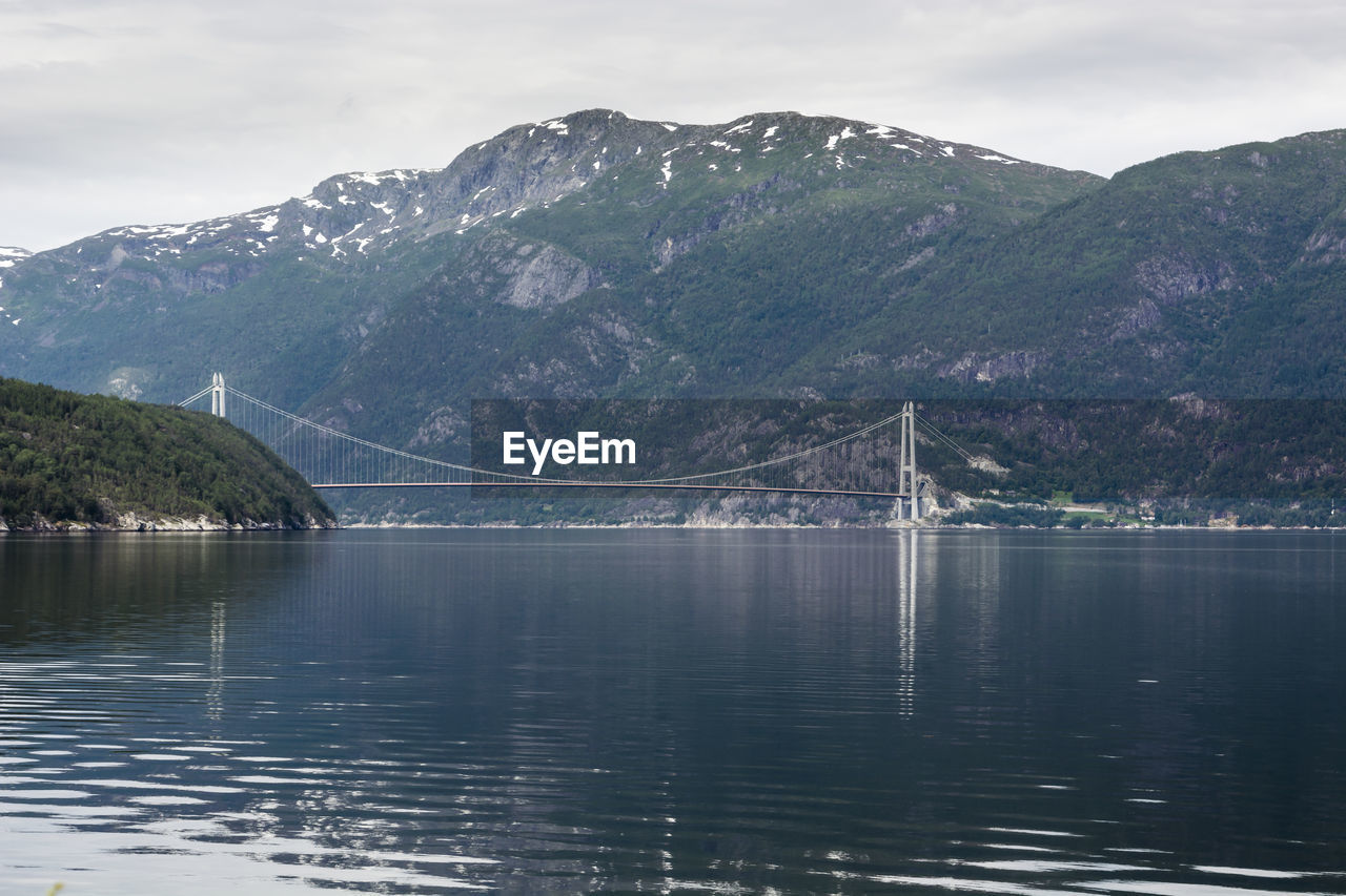 SCENIC VIEW OF BRIDGE OVER RIVER AGAINST MOUNTAINS