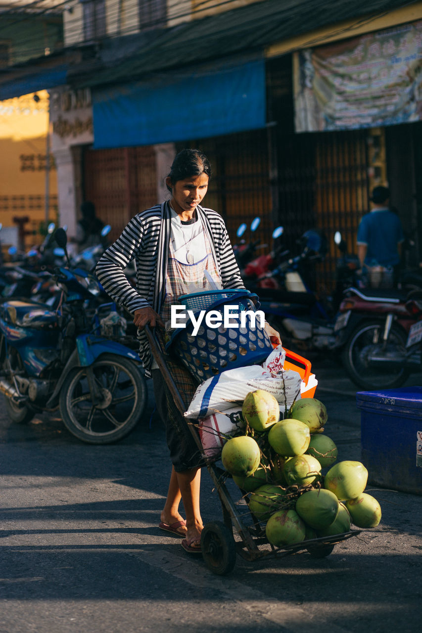 FULL LENGTH OF YOUNG MAN RIDING BICYCLE ON STREET AGAINST BLURRED BACKGROUND