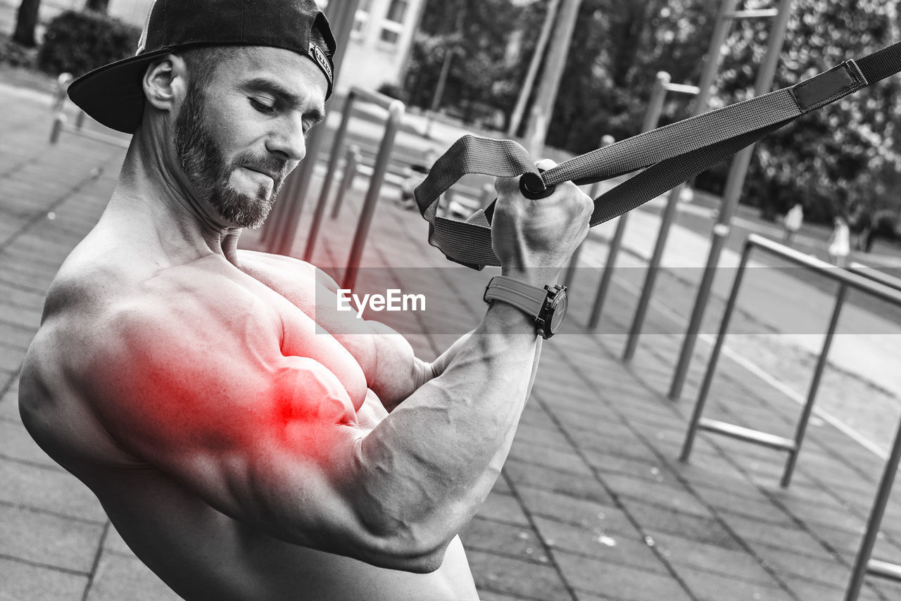 muscular build, adult, one person, men, sports, lifestyles, strength, athlete, exercising, person, sports training, human face, black and white, clothing, portrait, holding, young adult, activity, monochrome, vitality, macho, city, waist up, leisure activity, monochrome photography, black, day, bodybuilding, outdoors, white, human muscle, wellbeing, hat