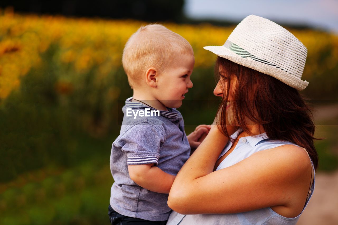 Mother carrying cute son while standing outdoors