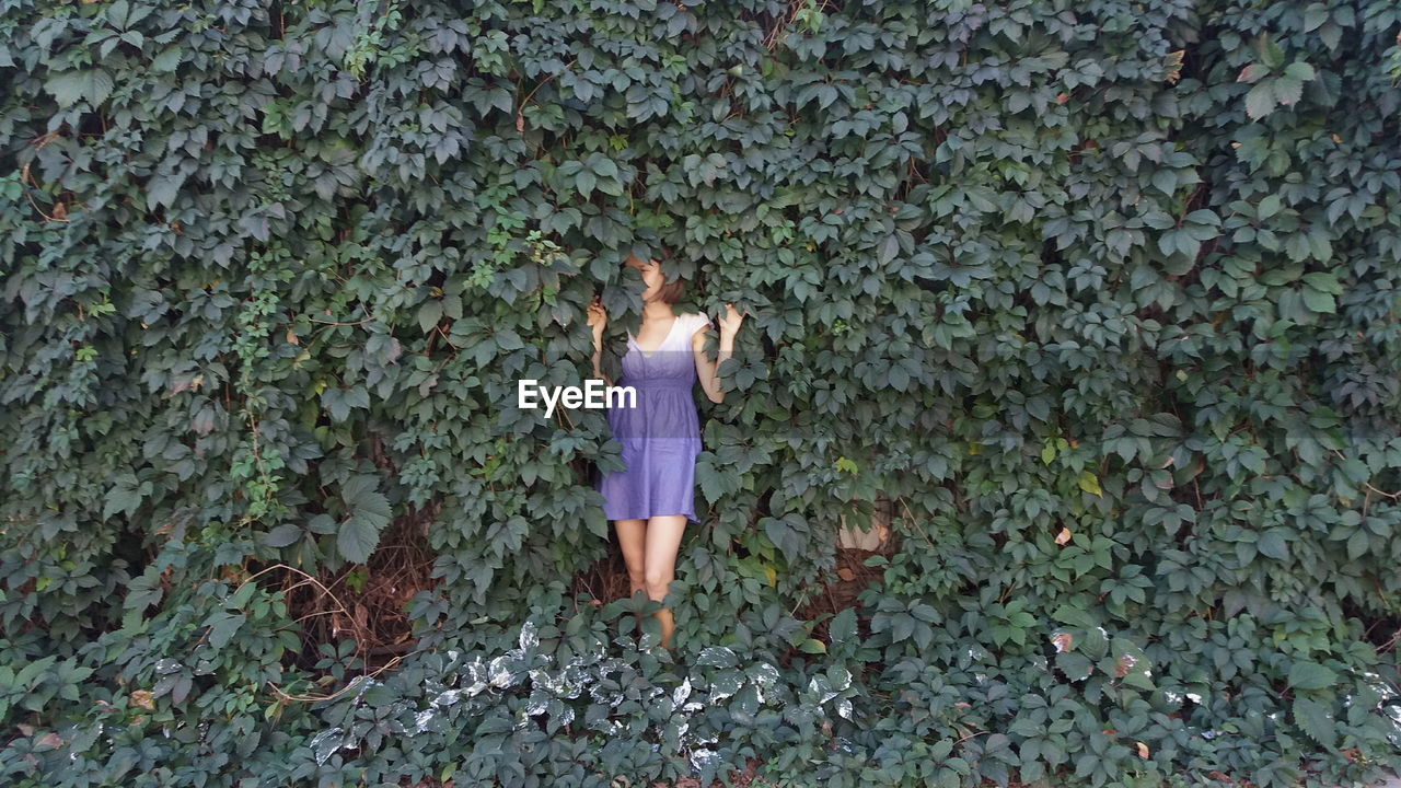 Woman standing by creeper plant