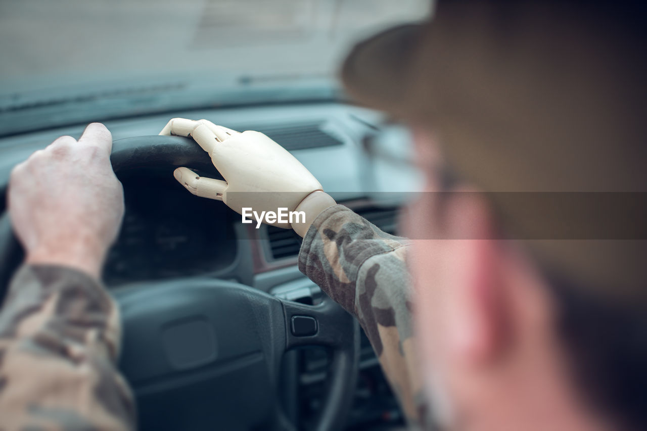 Midsection of man with prosthetic arm driving car