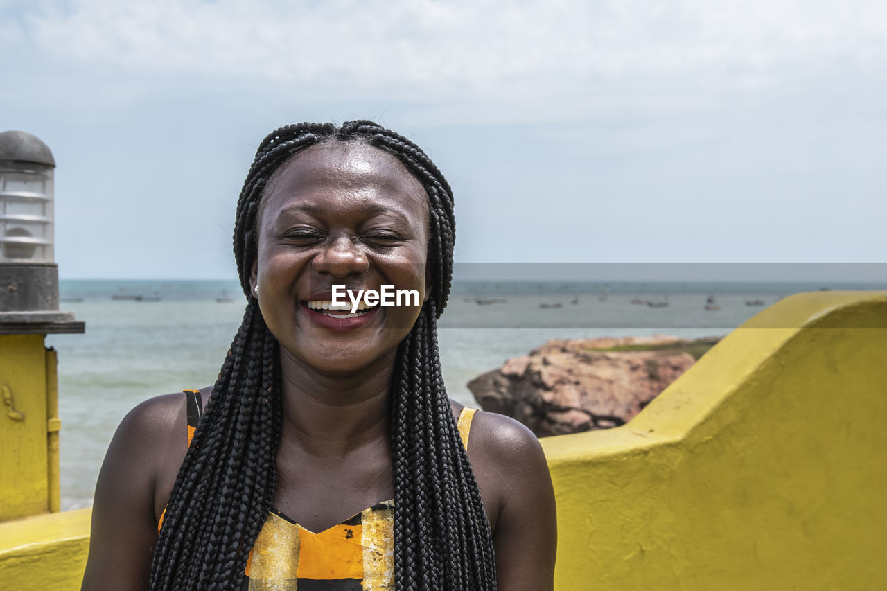 Happy africa woman from ghana stands on the coast in accra city.