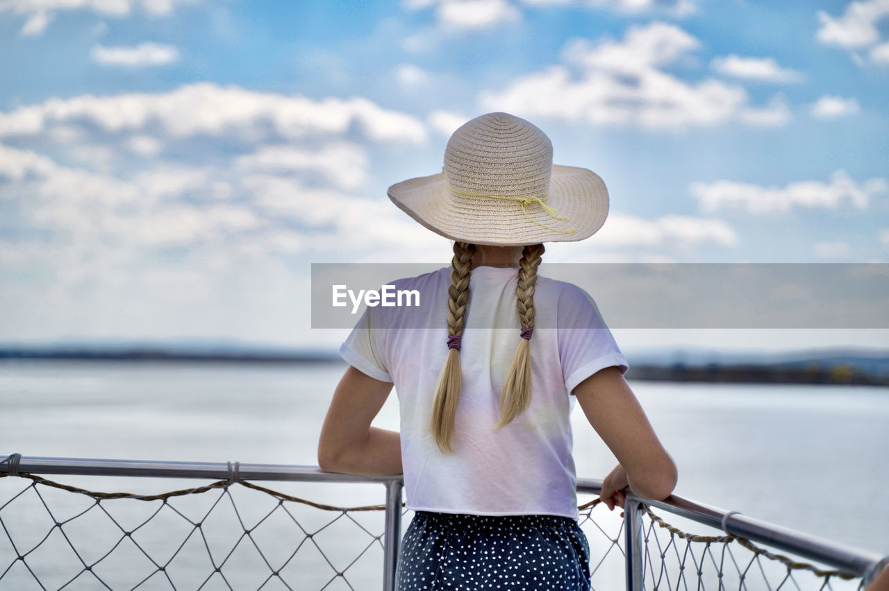 Midsection of woman standing by railing against sea