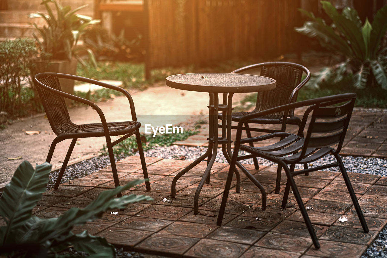 EMPTY CHAIRS AND TABLE IN BACKYARD