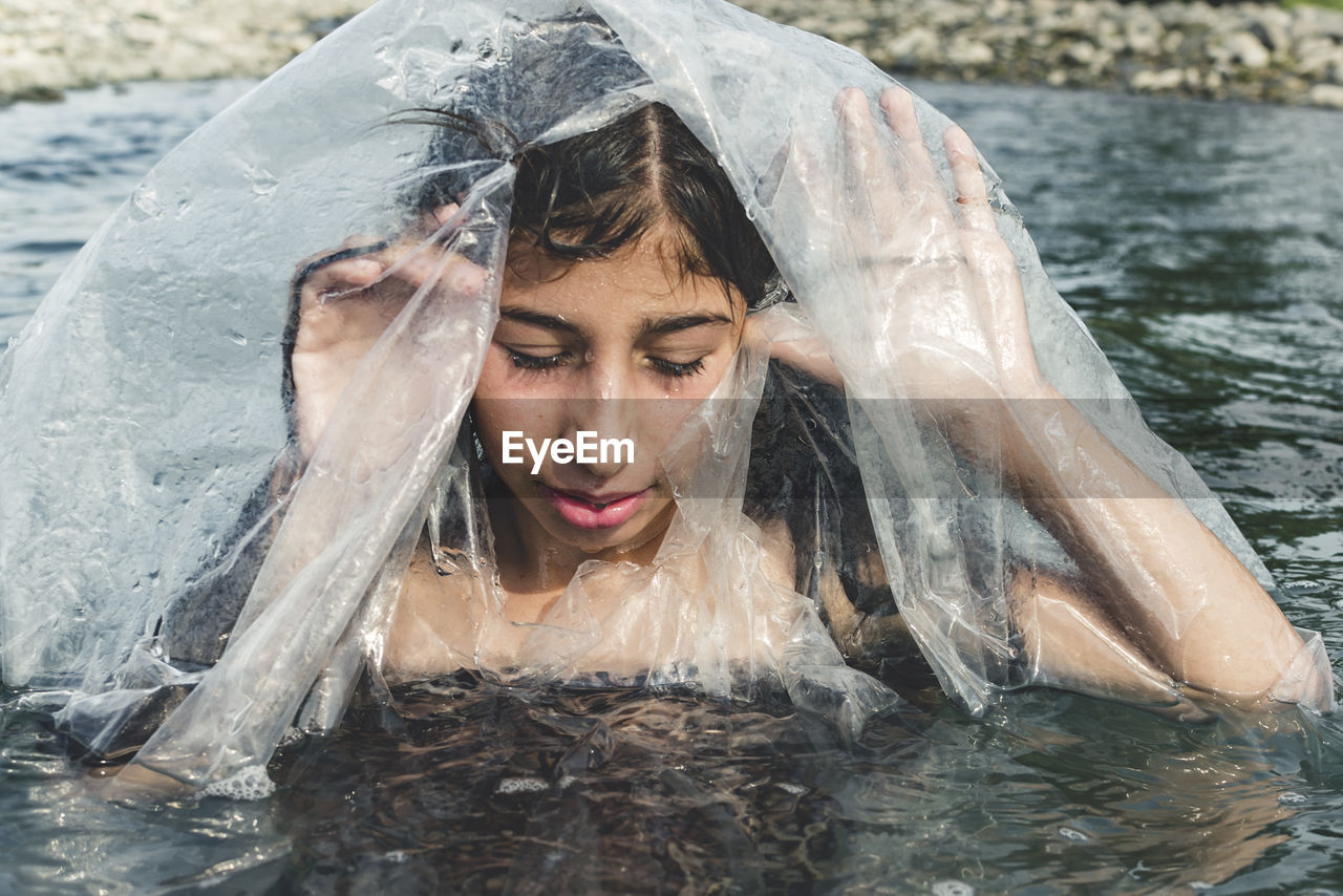 Close-up of girl amidst plastic in sea