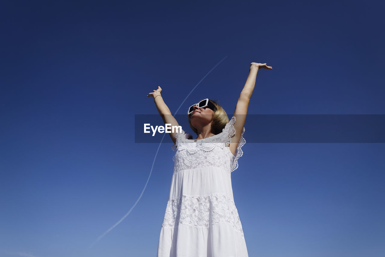 A happy, confident woman rejoices by raising her hands up to the flying plane. positive, motivation
