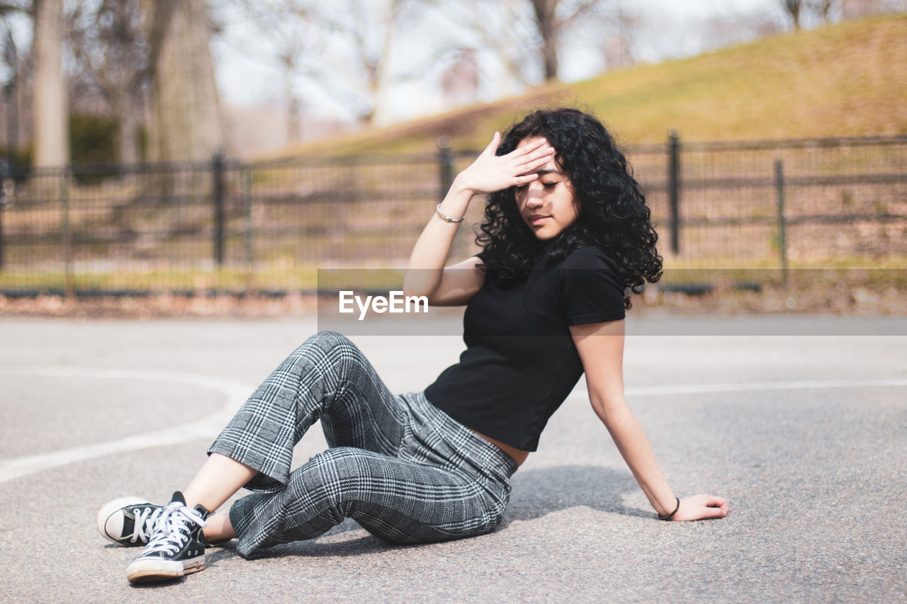 Woman shielding eyes while sitting on road