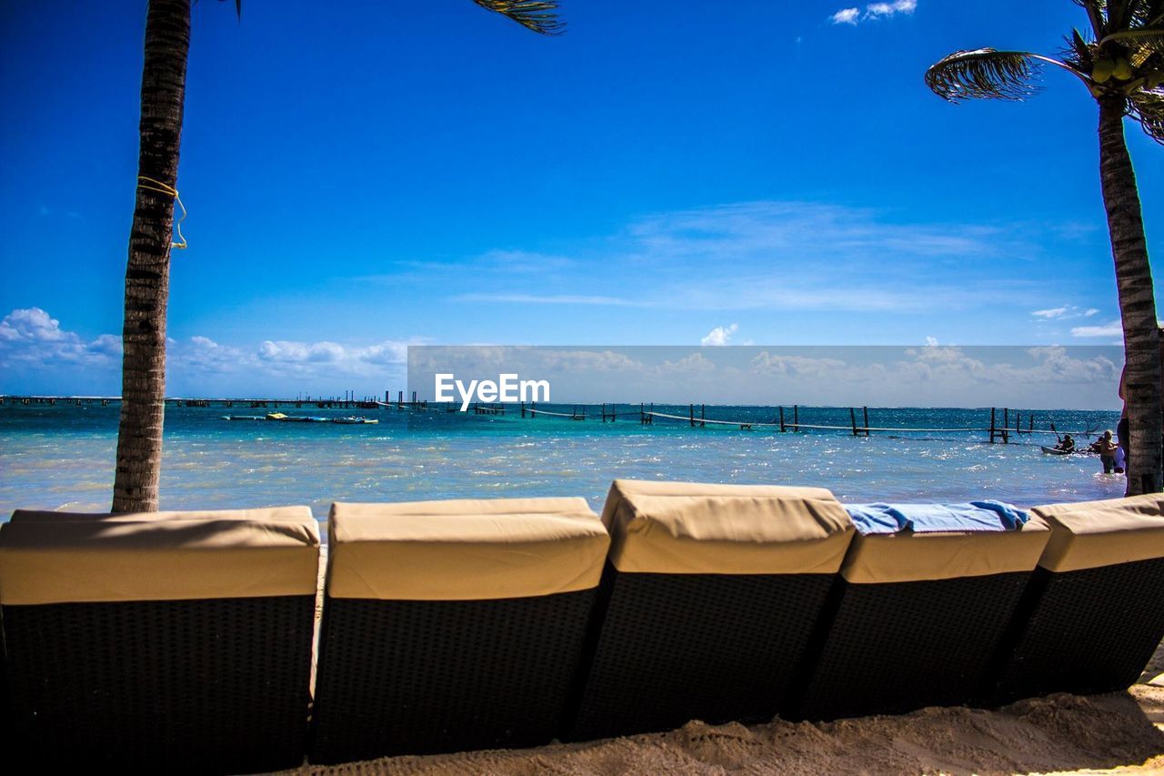 CHAIRS ON BEACH BY SEA AGAINST SKY