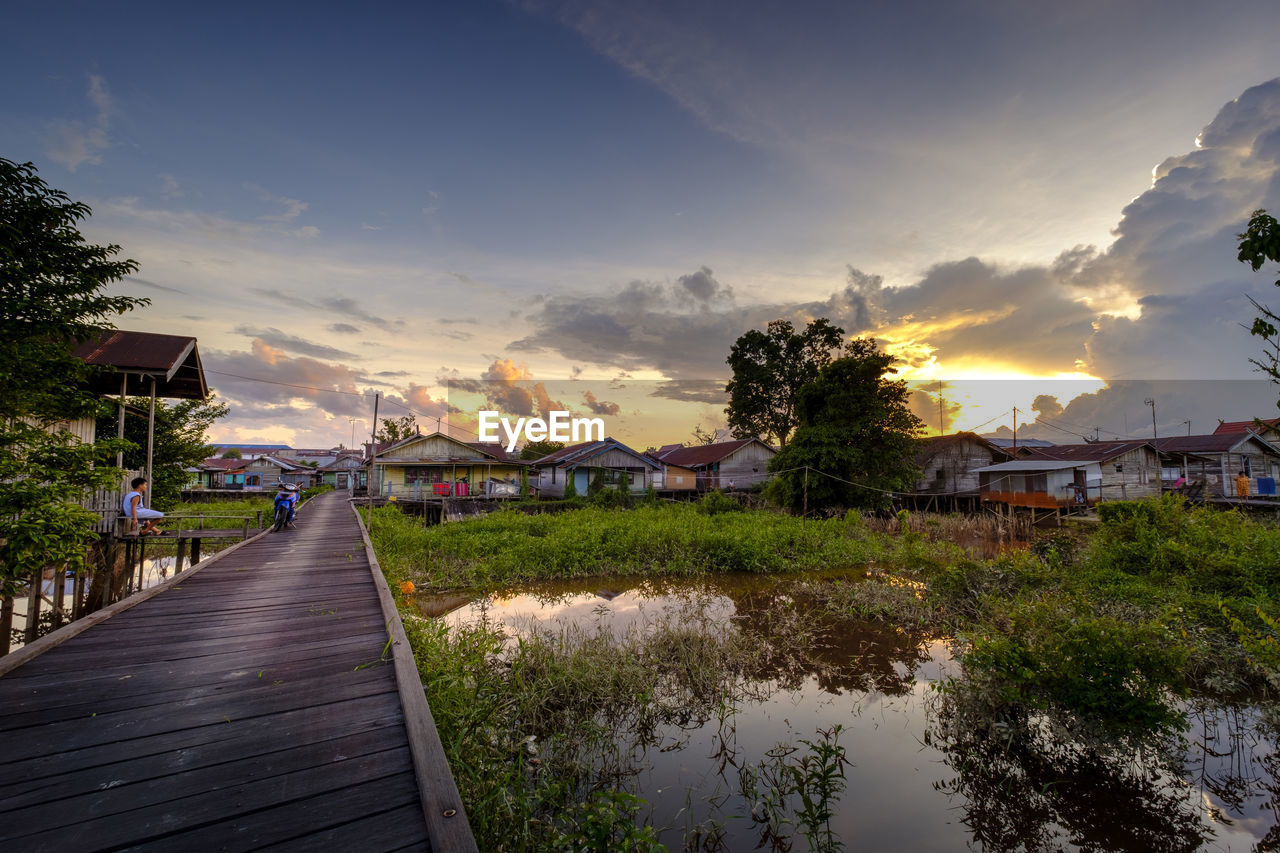 Canal amidst buildings against sky during sunset