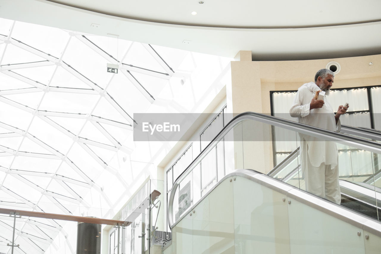 LOW ANGLE VIEW OF MAN STANDING AT STAIRCASE