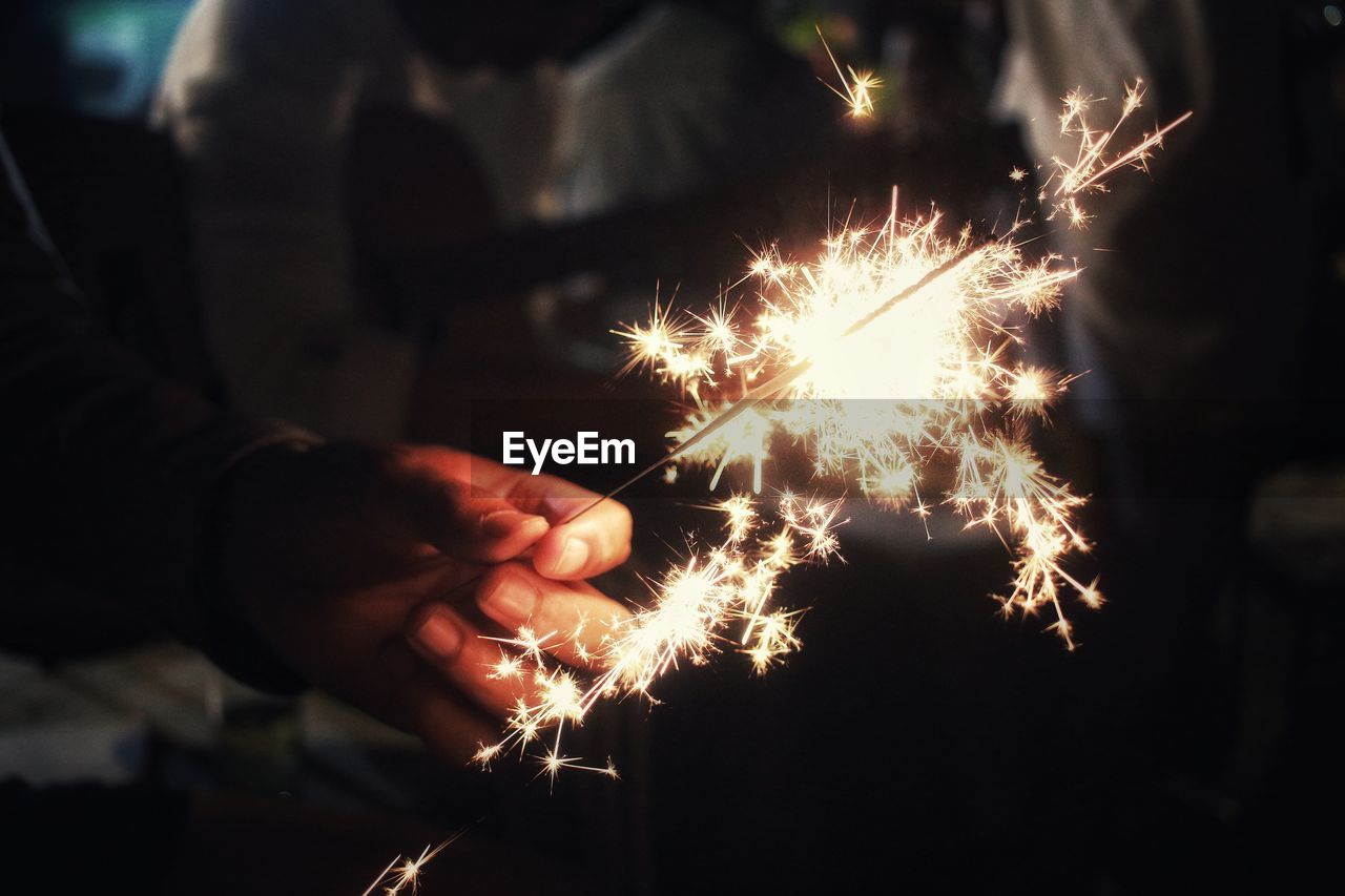 Close-up of hand holding sparkler at night