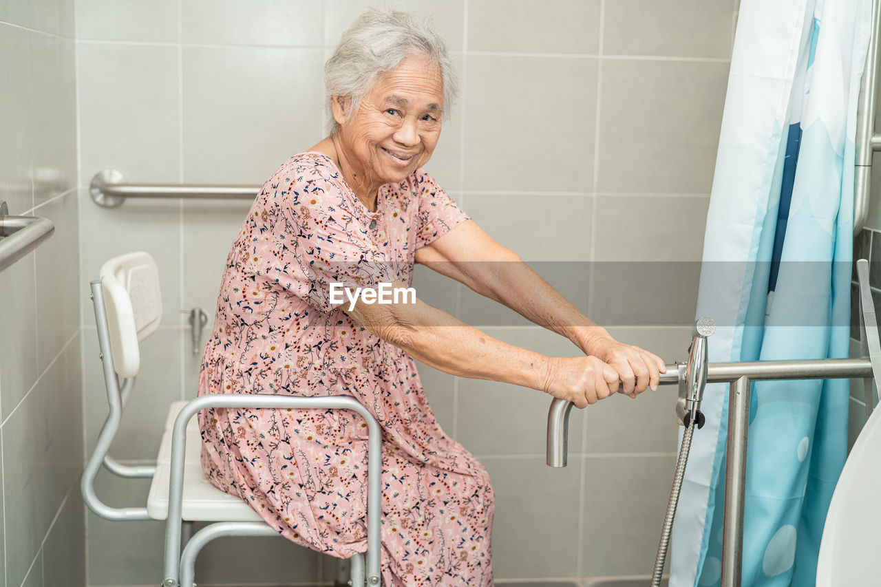 Asian senior woman patient use toilet bathroom handle security concept.