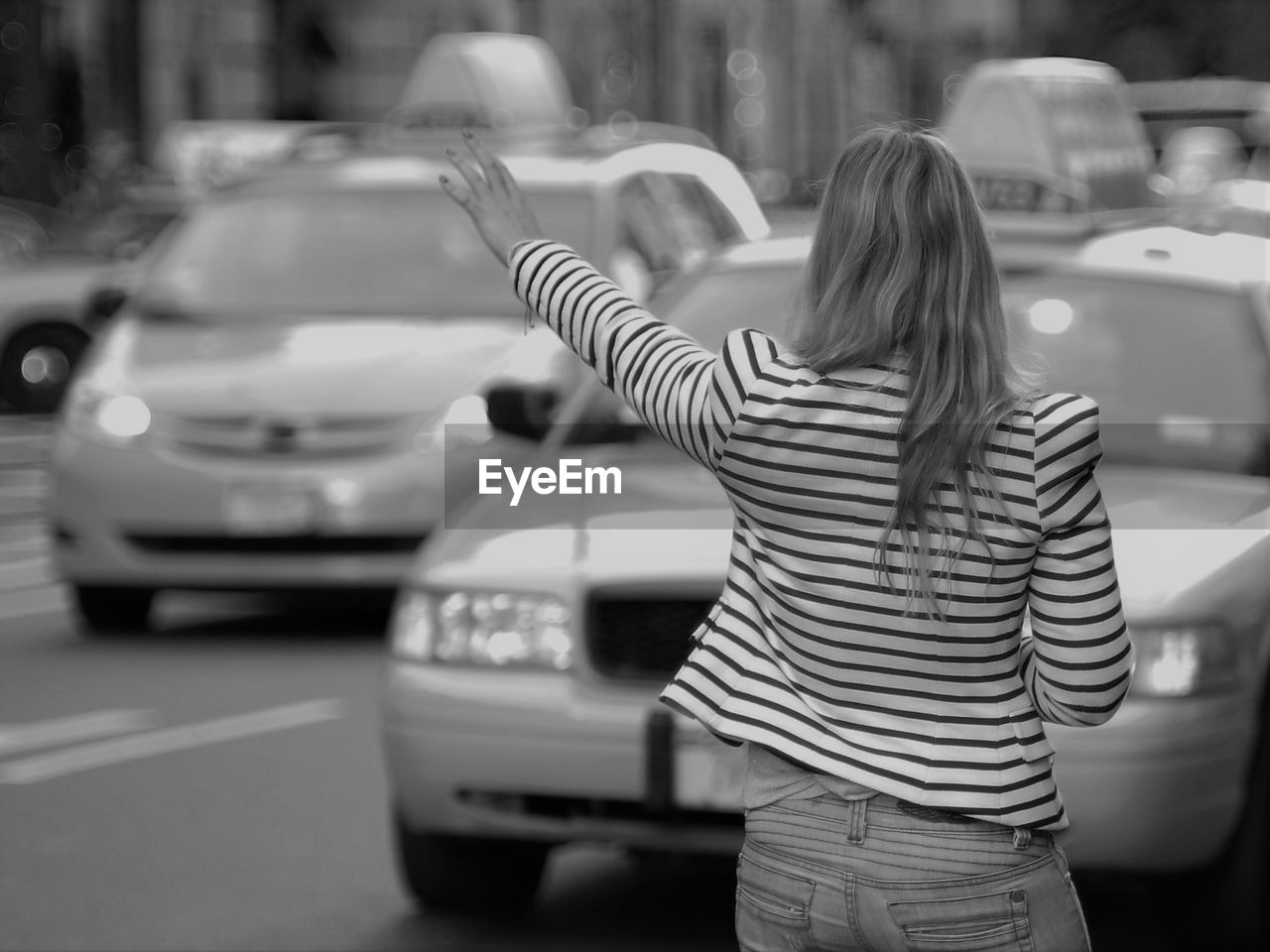 Rear view of woman stopping car while standing on street in city