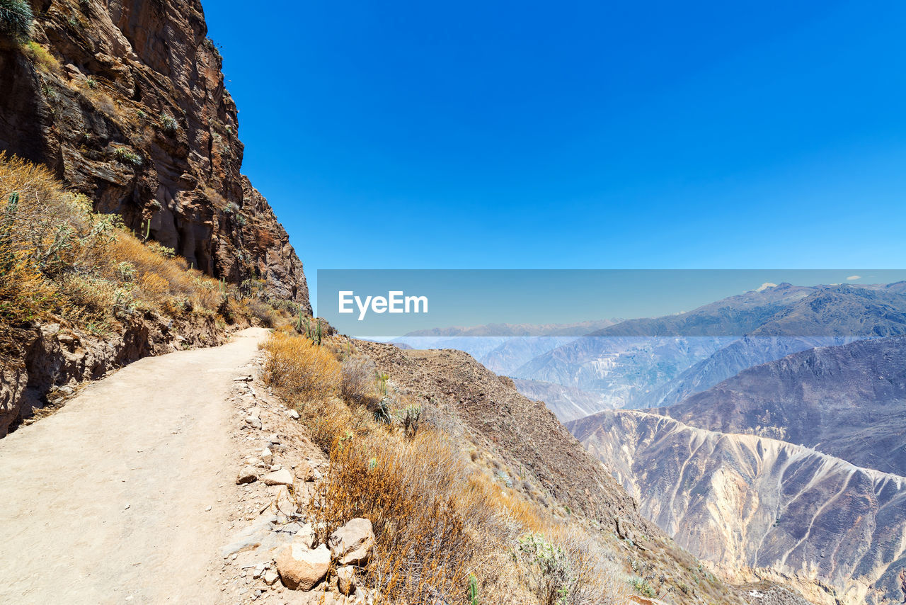 Road on mountain against clear blue sky 