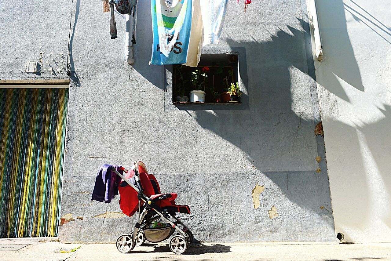 Baby carriage on footpath against building