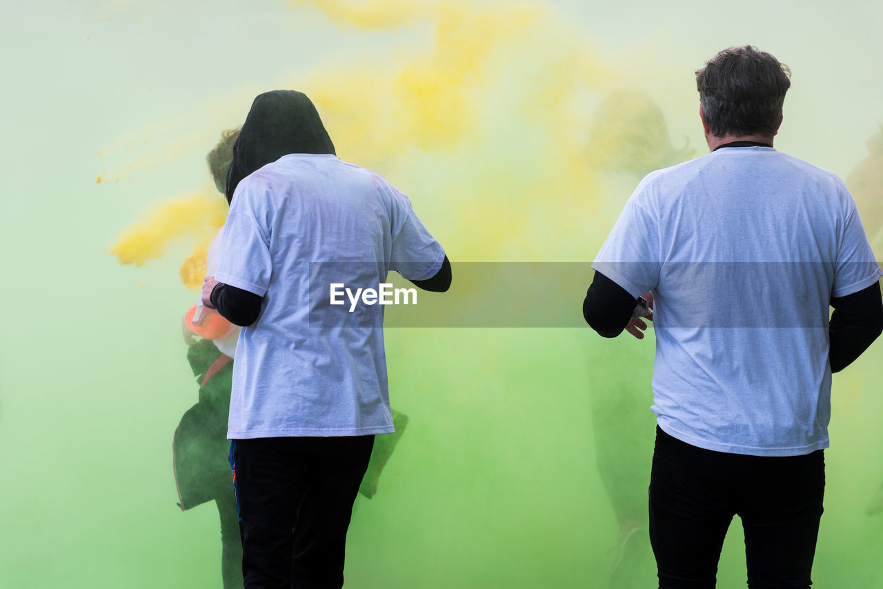 Rear view of man and woman standing amidst powder paint