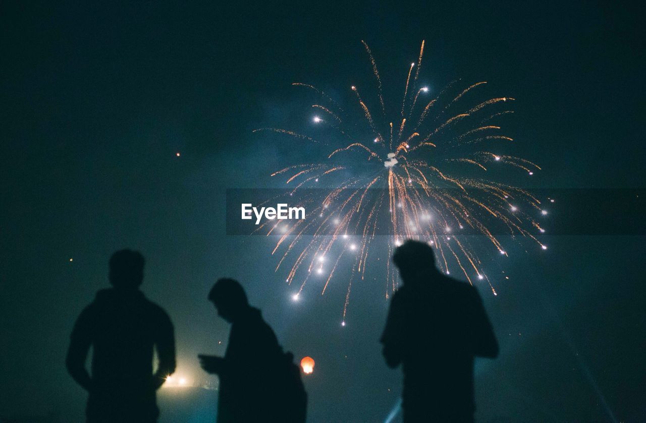 Silhouette people watching fire crackers against clear sky