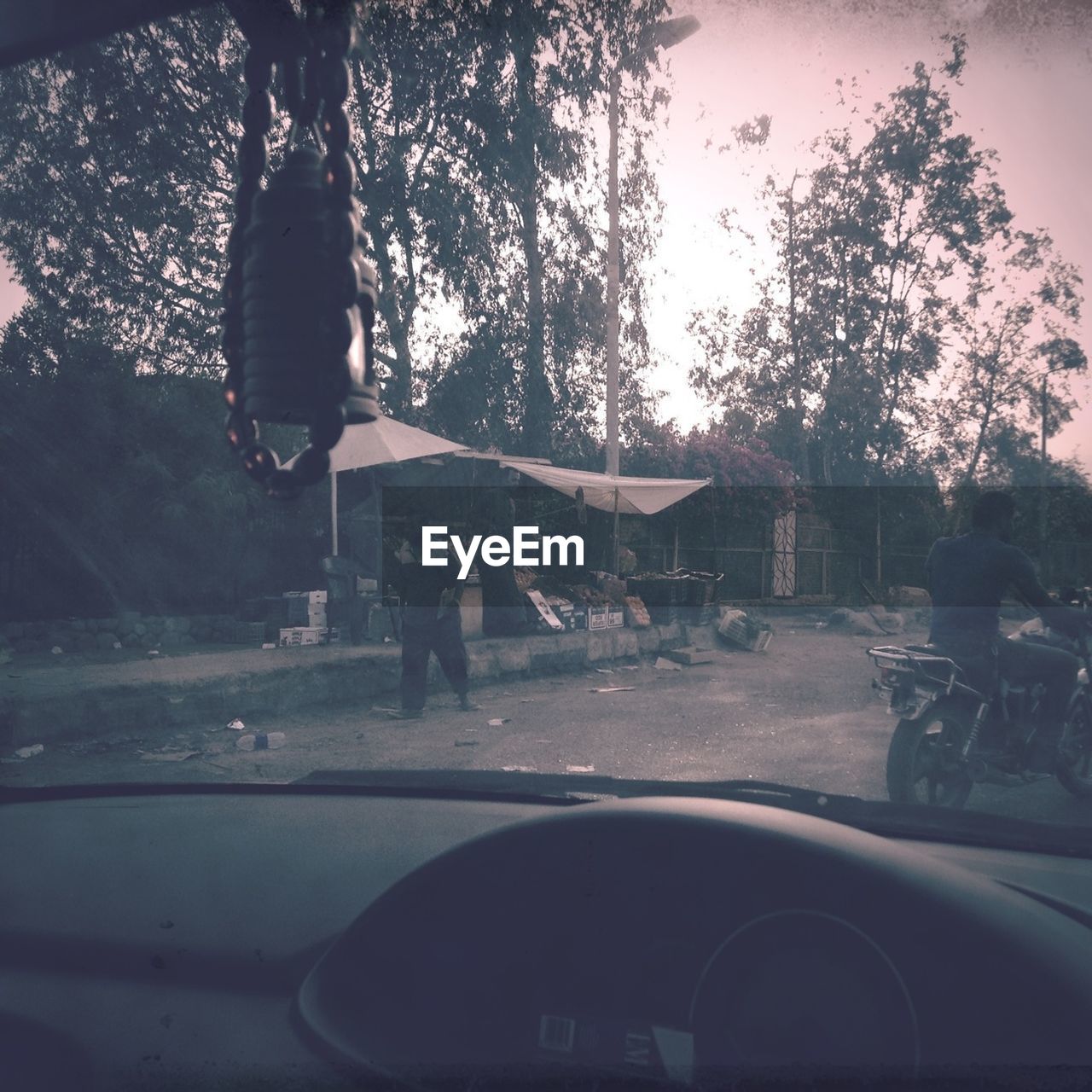 View of market stall on sidewalk of street from car windshield