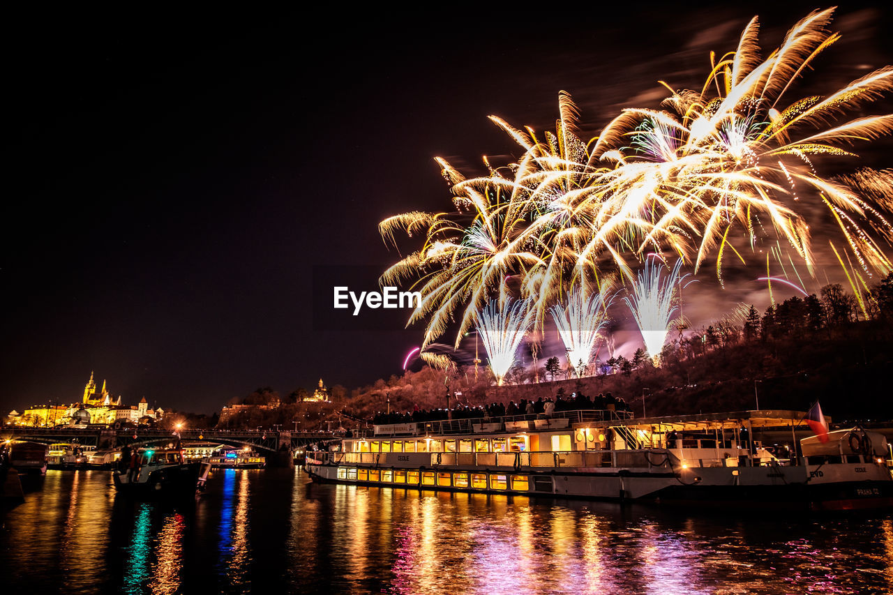 Firework display over river against sky at night