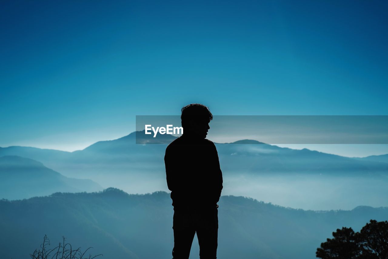 SILHOUETTE MAN LOOKING AT MOUNTAIN AGAINST SKY