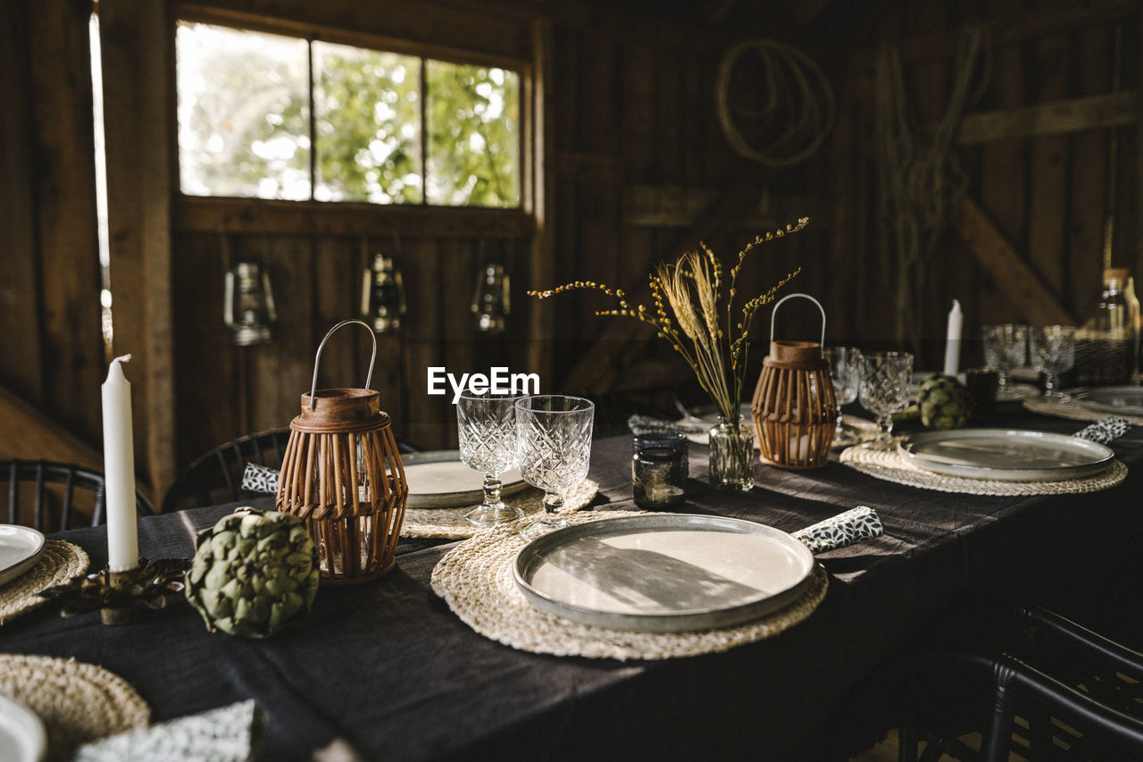 Plates and glasses arranged on dining table during social gathering