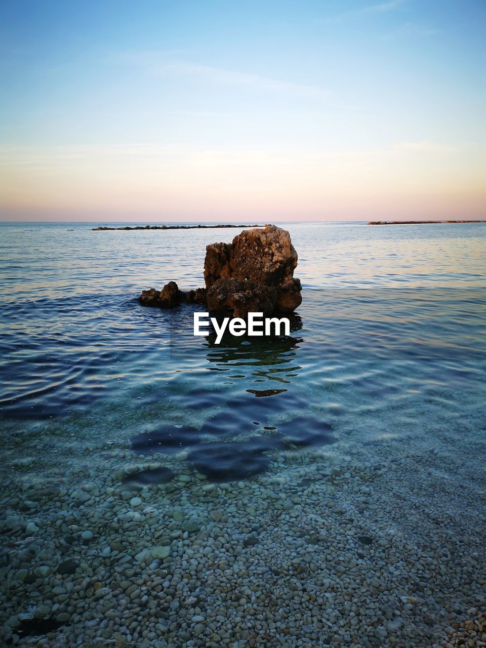 Rocks on sea against sky during sunset