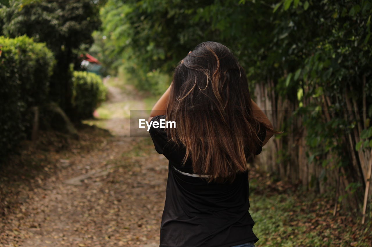 REAR VIEW OF WOMAN AGAINST TREE