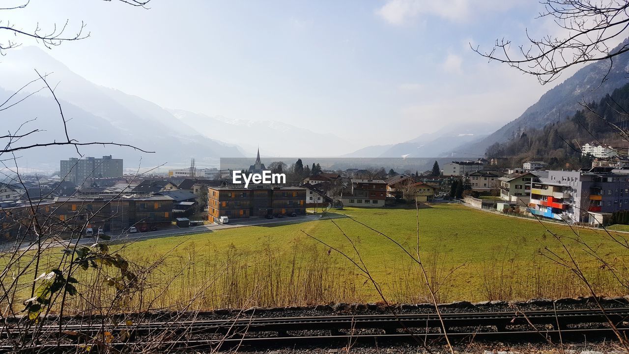 Scenic view of agricultural field by houses against sky