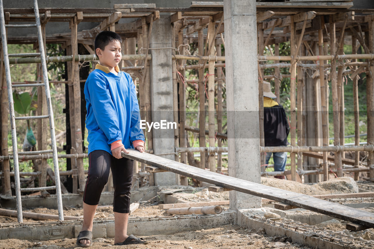 SIDE VIEW OF MAN STANDING BY CONSTRUCTION SITE